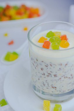 İçinde yulaf ezmesi, chia, keten tohumu ve yoğurt bulunan şekerli meyvelerle süslenmiş bir bardağa yakın plan. seçici odak