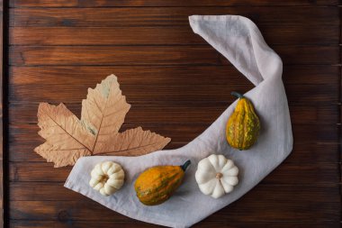 Renkli mini balkabakları, su kabakları ve ahşap arka planda kuru yaprak, üst manzara. Sonbahar yatağı. Şükran Günü kutlaması. Metin için alanı kopyala.