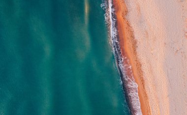 Deniz kıyısı ve kumsalın havadan görünüşü. Doğal arka plan, İHA fotoğrafçılığı. Tam üstte.