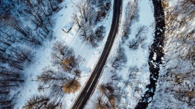 Dağ yolu, ağaçlar ve nehrin karların altındaki yüksek açılı hava manzarası. Kış manzarası, kuş bakışı manzara..
