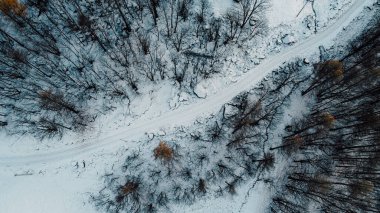 Karla kaplı dağ yolu ve kış ormanlarının havadan yüksek açılı manzarası. Kır yolu yolu, kuş bakışı..