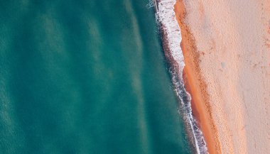 Deniz kıyısı ve kumsalın havadan görünüşü. Doğal arka plan, İHA fotoğrafçılığı. Tam üstte.