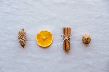 Çam kozalakları, tarçın çubukları, kuru portakal dilimleri ve doğal arka planda ceviz gibi doğal dekorasyonlarla tatil yatıyordu. Sıfır Noel konsepti. Plastiksiz tatil. 