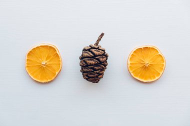 Çam kozalakları ve beyaz ahşap arka planda kuru portakal dilimleri gibi doğal dekorasyonlarla tatil yatıyordu. Sıfır Noel konsepti. Plastiksiz tatil. Sürdürülebilir yaşam tarzı.