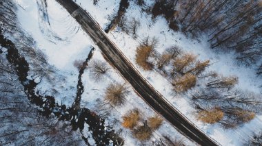 Dağ yolu, ağaçlar ve nehrin karların altındaki yüksek açılı hava manzarası. Kış manzarası, kuş bakışı manzara..