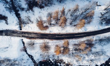 Dağ yolu, ağaçlar ve nehrin karların altındaki yüksek açılı hava manzarası. Kış manzarası, kuş bakışı manzara..