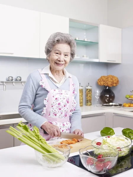 Äldre kvinna förbereder måltid i köket — Stockfoto