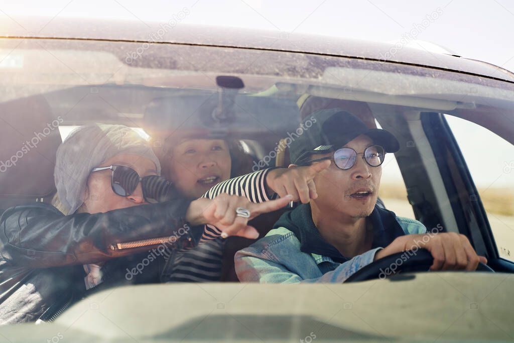 group of happy asian friends enjoying a sightseeing trip by car