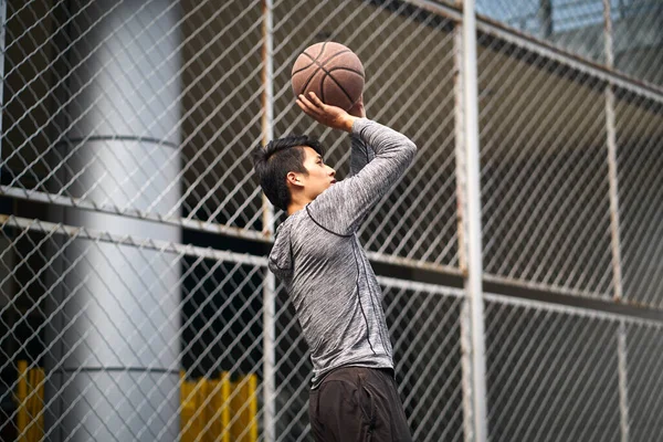 Genç Asyalı Erkek Basketbolcu Çitlerle Çevrili Bir Sahaya Atlıyor — Stok fotoğraf