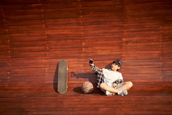 十代のアジアのスケートボーダー少年は携帯電話を使って自撮り — ストック写真