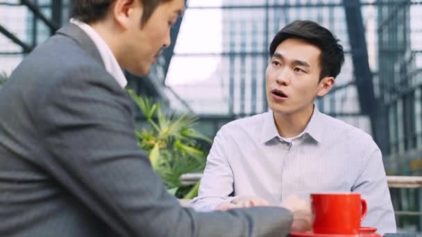 Two Asian Business People Sitting Outdoor Coffee Shop Having Discussion — Video Stock