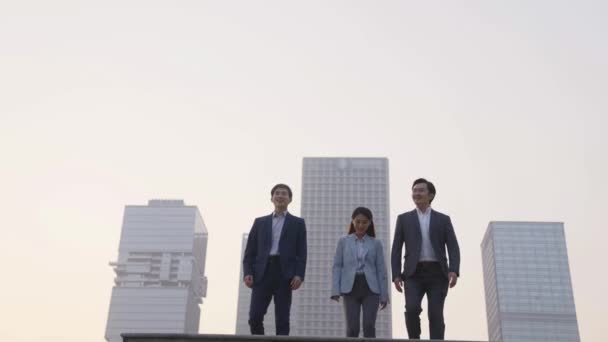 Zespół Trzech Azjatyckich Biznesmenów Świętujących Sukces Skacząc Nowoczesną Panoramą Miasta — Wideo stockowe
