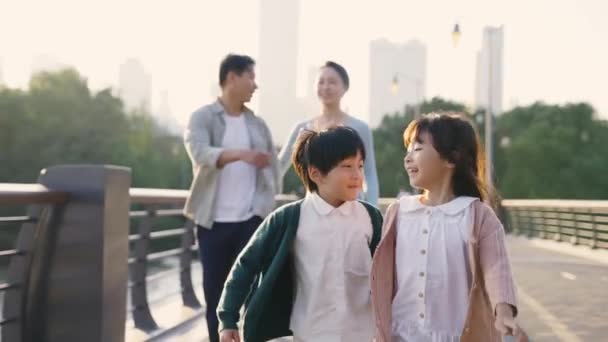 快乐的亚洲家庭 有两个孩子在城市公园的一座桥上散步 — 图库视频影像