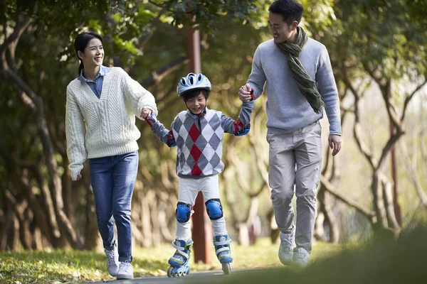 Liefdevolle Aziatische Ouders Onderwijzen Zoon Rolschaatsen Buiten Stadspark — Stockfoto