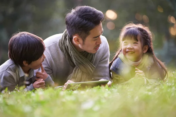 Asiático Padre Acostado Frente Hierba Contar Historia Dos Niños Feliz — Foto de Stock