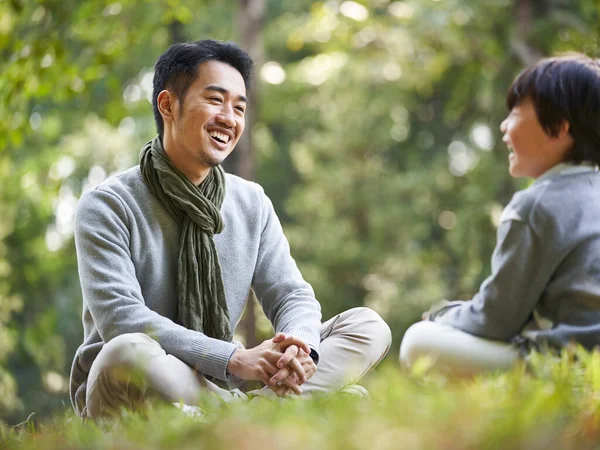 Asian Father Son Sitting Grass Having Pleasant Conversation Outdoors Park — Stock Photo, Image