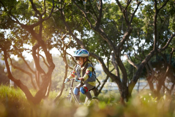 在城市公园里 可爱的快乐的亚洲小女孩 戴着头盔 骑着全套护具骑自行车 — 图库照片