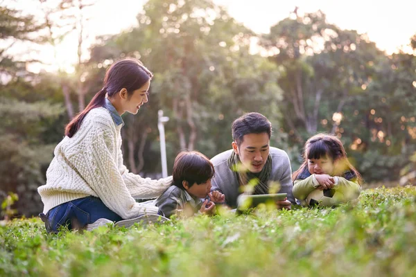 都会の公園でリラックスしている2人の子供を持つアジア系の家族 — ストック写真