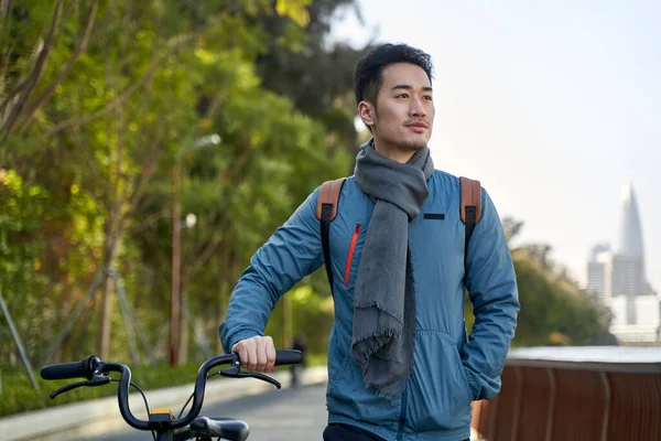 アジア系の若者が公共公園を自転車で歩き — ストック写真