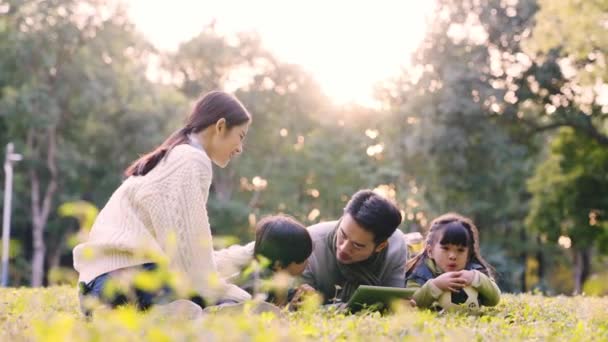 一对年轻的亚洲夫妇和两个孩子在公园里放松一下 — 图库视频影像