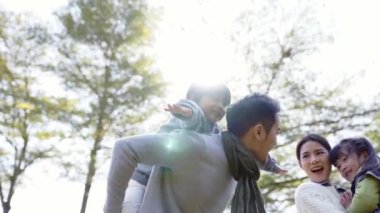İki çocuklu genç Asyalı bir aile parkta eğleniyor.