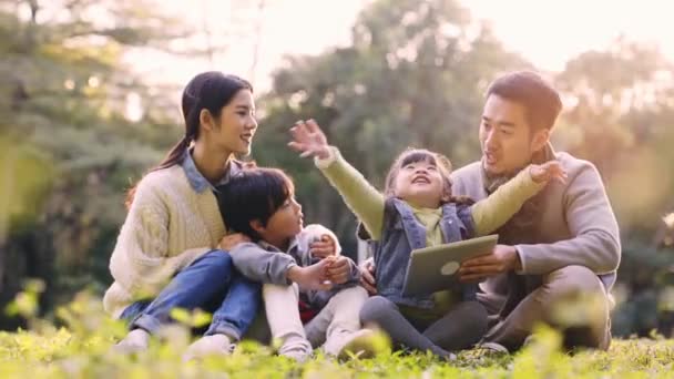 Азиатская Семья Двумя Детьми Сидящими Траве Разговаривая Расслабляющий Открытом Воздухе — стоковое видео