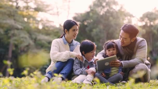 有两个孩子的年轻的亚洲家庭在公园的户外放松 — 图库视频影像