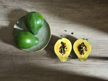 iki bütün ve iki yarım yeşil papaya ahşap yüzeyde