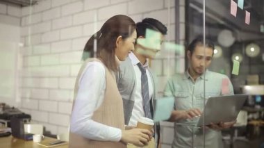 Küçük Asyalı girişimciler ofis toplantı odasında yapışkan bir notla iş stratejilerini tartışıyorlar.. 