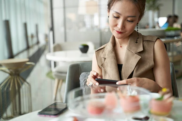 Mature Asian Woman Looking Cellphone While Having Afternoon Tea Modern — Stockfoto