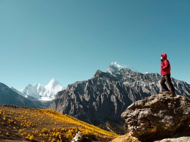 Yading, Daocheng County, Sichuan Eyaleti, Çin 'deki Yangmaiyong (Tibet' te Jampayang) dağ zirvesine bakan Asyalı bir adam.