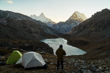 Asyalı kampçı, dağ ve gölün fotoğrafını çekiyor. Yading Ulusal Parkı, Daocheng Bölgesi, Sichuan Bölgesi, Çin