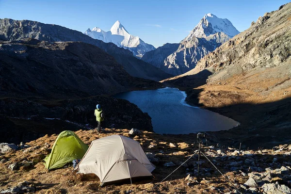 Asyalı kadın fotoğrafçının arkadan görünüşü Yading Ulusal Parkı, Daocheng İlçesi, Sichuan Bölgesi, Çin 'deki kamp alanına bakıyor.