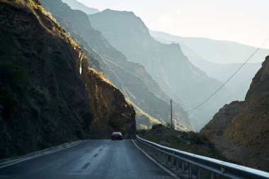 Çin 'in Sichuan eyaletindeki kayalık dağlarda otoyolda giden araba.