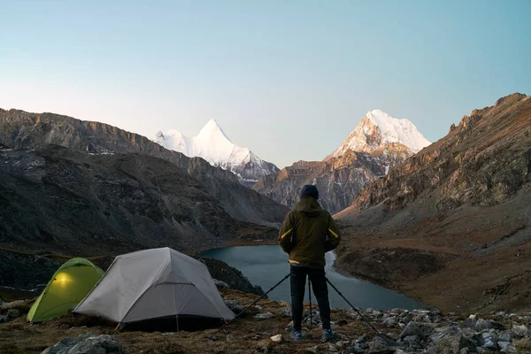 Asyalı kampçı, dağ ve gölün fotoğrafını çekiyor. Yading Ulusal Parkı, Daocheng Bölgesi, Sichuan Bölgesi, Çin