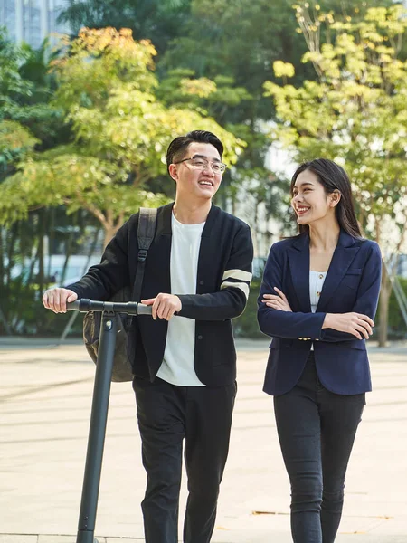 young asian man and woman walking chatting on street happy and smiling