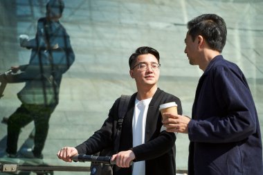 İki Asyalı genç arkadaş sokakta yürürken sohbet ediyorlar.