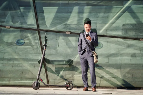 Молодой Азиатский Бизнесмен Электрическим Скутером Смотрит Мобильный Телефон Открытом Воздухе — стоковое фото
