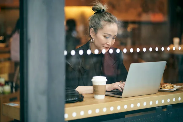 Orta Yaşlı Asyalı Bir Kadınının Bilgisayarla Kahve Dükkanında Çalışırken Çekilmiş — Stok fotoğraf
