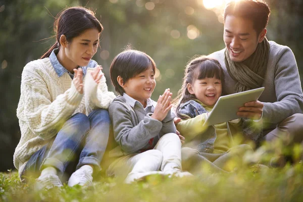 Young Asian Family Two Children Sitting Grass Outdoors Park Watching — 图库照片