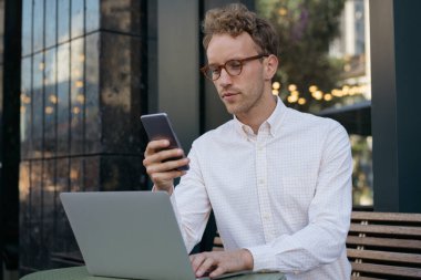 Ofisteki dijital ekrana bakan düşünceli bir işadamı elinde cep telefonu, dizüstü bilgisayar kullanıyor. Şık bir serbest yazar, işyerinde online çalışıyor. Modern teknolojiyi kullanan yakışıklı öğrenci.
