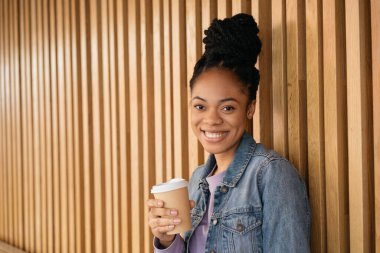Elinde kahve fincanı tutan gülümseyen Afro-Amerikan kadın dışarıda oturan kameraya bakıyor. Kahve molası