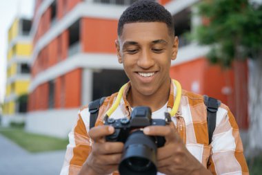 Profesyonel Afro-Amerikan fotoğrafçı portresi sokakta resim seçiyor. Dışarıda dijital kamera tutan mutlu bir turist. Seyahat kavramı