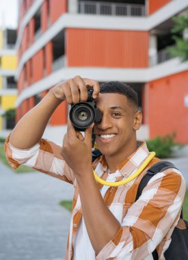 Profesyonel Afro-Amerikan fotoğrafçı portresi. Sokakta kameraya bakarak fotoğraf çekiyor. Dışarıda dijital kamera tutan bir turist, kopyalama alanı. Tatil, seyahat kavramı