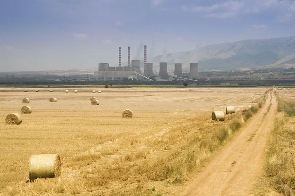Balle rotonde di paglia nel prato vicino alla centrale elettrica a combustibile, Grecia — Foto Stock