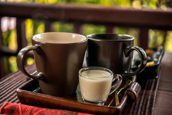 Чашка чая с молоком за деревянным столом — стоковое фото