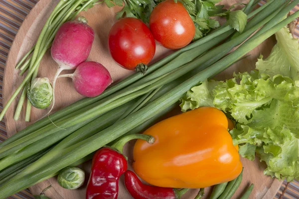 Fresh vegetables on a round wooden chipboard — Stock Photo, Image