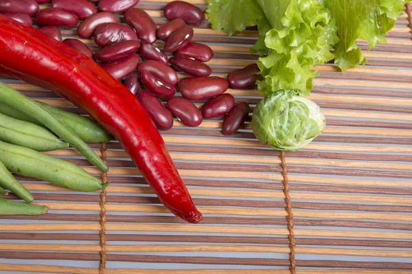 Kidney bean, paprika and lettuce on bamboo mat — Stock Photo, Image