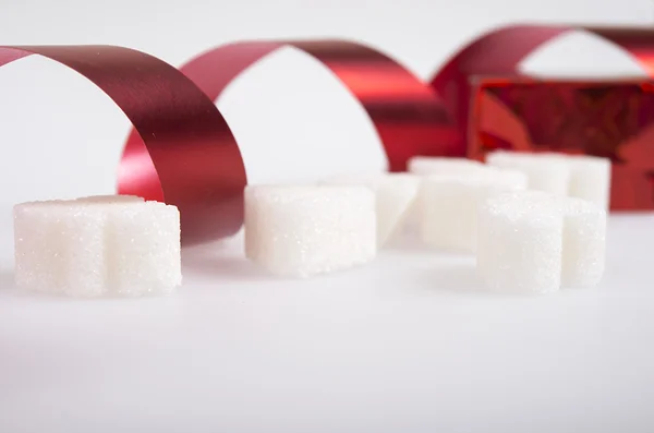 Sugar cubes with red ribbon. — Stock Photo, Image