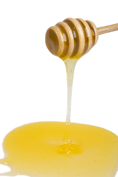Stream of honey on the wooden honey dipper — Stock Photo, Image